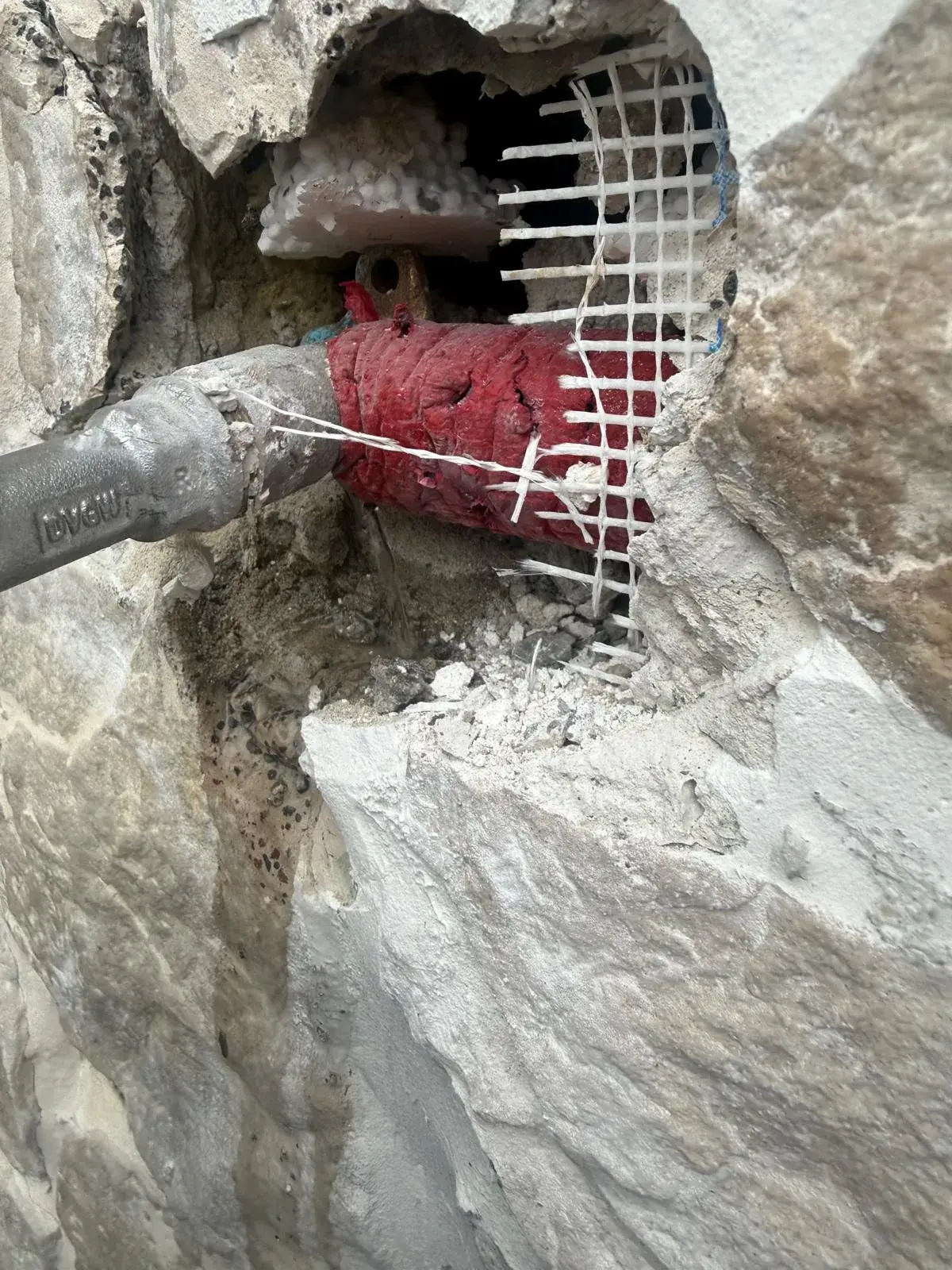 Lokalisierter Rohrbruch: Wasseraustritt an einer freigelegten Druckleitung hinter der Wand